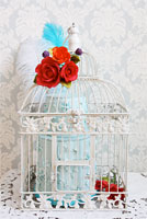 Antique birdcage with pale blue floral cake complimented with orange and red sugar roses.