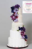 Drenched in pearls and covered in a variation of purple sugar flowers